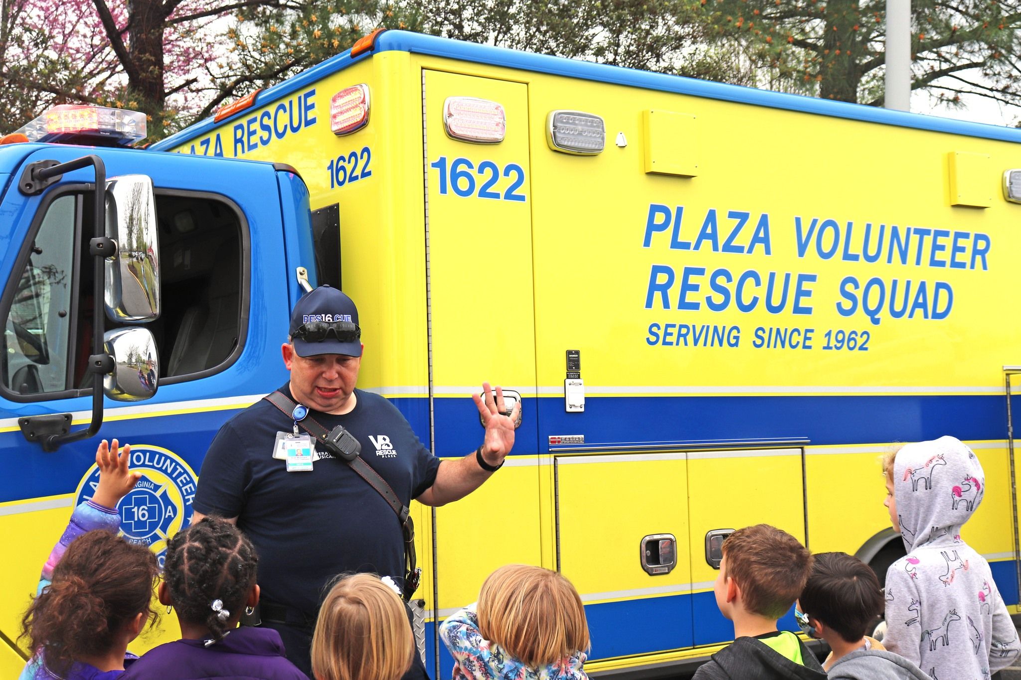 EMS Volunteer, Kyle, speaks with school children in front of Plaza Ambulance
